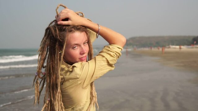 Portrait of a cheerful young hippie downshifter girl with dreadlocks on beach