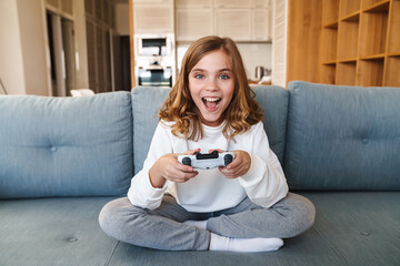 Photo of excited nice girl smiling and playing video game with joystick © Drobot Dean