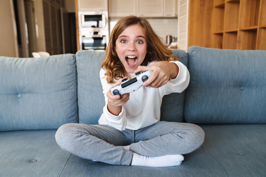 Photo of excited nice girl smiling and playing video game with joystick