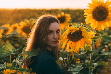Girl in a green dress and long blond hair in a sunflower field with backlight on the hair during sunset. The concept of summer and sun. Sunflower season in Israel. Celebrating life.