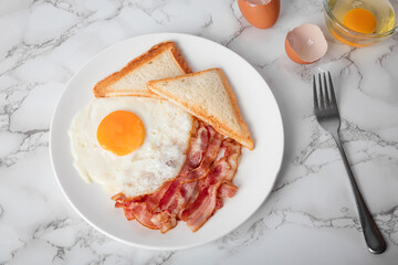 Breakfast with sunny side eggs, bacon and toast bread on a plate