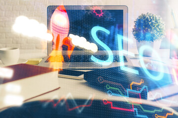 Double exposure of table with computer and seo drawing hologram. Search optimization concept.