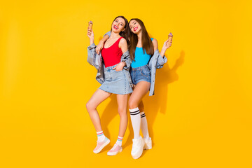 Obraz premium Full size photo positive youth sisters embrace hug enjoy summer free time holiday hold ice cream scoops wear red blue singlet jeans denim legs isolated bright color background