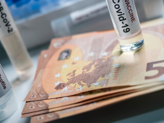 Coronavirus vial on euro banknotes, conceptual image