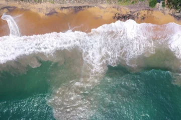  aerial drone bird view shot of the sea shore with turquoise blue water, large white waves and foam, empty beach with yellow sand, black rocks forming beautiful textures, patterns, shapes. Sri Lanka © Liza