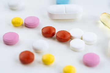 Different colorful pills on the white table background