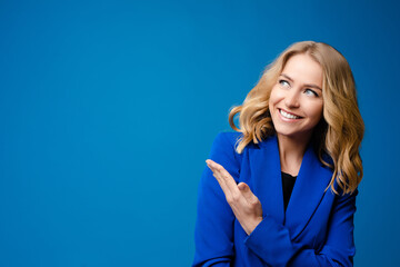 Stock photo portrait of a smiling gorgeous blonde Caucasian woman in blue jacket showing at...