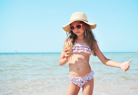 Little cute girl holds ice cream on the beach.