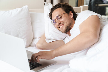 Smiling young man laying on a pillow in bed