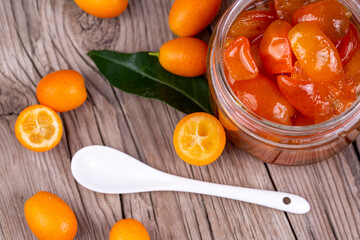 Homemade kumquat jam in jar and fresh kumquats, top view