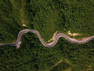 Mountain winding zig zag road. Top aerial view: cars driving on road from above.