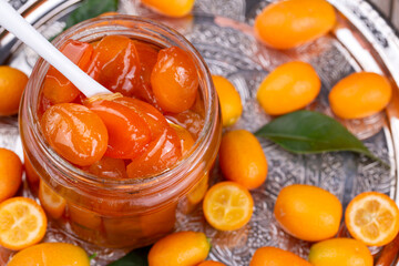 Homemade kumquat jam in jar and fresh kumquats, top view