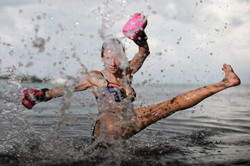 Beautiful woman in pink boxing glows kicking with the leg with splash water at the Caribbean sea on...