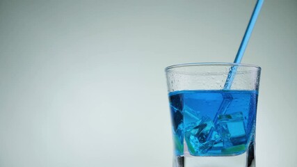 Glass of blue drink with ice and kiwi rotate on a white background.