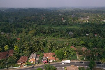 Fototapeta na wymiar natural aerial drone bird view day shot of the sea shore with a road, beautiful villas and green forest trees. Pitiwella, Sri Lanka