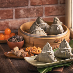 Zongzi - Chinese rice dumpling zongzi in a steamer on wooden table with red brick, window background at home for Dragon Boat Festival concept, close up.
