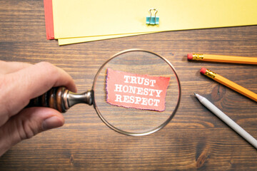 TRUST, HONESTY, RESPECT concept. Man's hand, holding magnifying glass