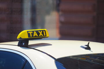 Taxi sign on roof of car on city street, taxi