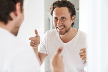 Attractive young man standing in front of the bathroom mirror