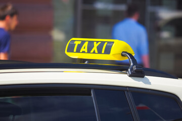 Taxi sign on roof of car on city street