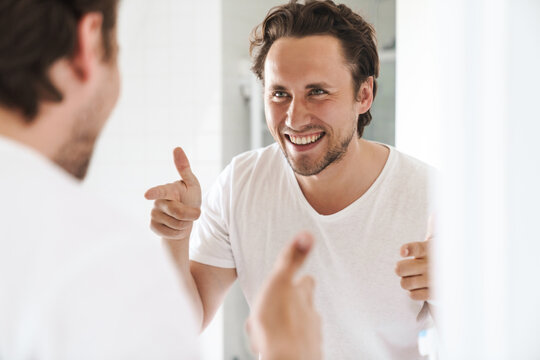 Attractive young man standing in front of the bathroom mirror