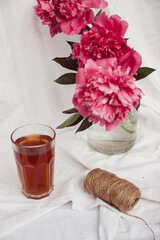 glass with tea and a bouquet of flowers on a white vintage background. flowers red peonies