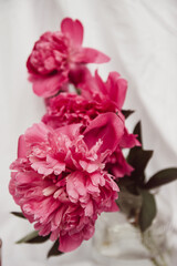 Fototapeta premium glass with tea and a bouquet of flowers on a white vintage background. flowers red peonies