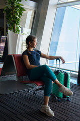 Sport girl sitting with luggage in duty free zone