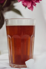 glass with tea and a bouquet of flowers on a white vintage background. flowers red peonies