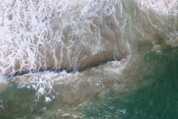 Fototapeta na wymiar aerial drone bird view shot of the sea surface with turquoise blue water, large white waves, foam and underwater sand forming beautiful textures, patterns, shapes. Sri Lanka