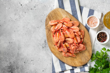 Prawns on a wooden Board on the light gray kitchen table. Lots of shrimp on the serving Board. The view from the top