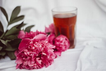 glass with tea and a bouquet of flowers on a white vintage background. flowers red peonies