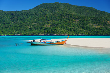 Fototapeta na wymiar Boat on tropical sea coast with white sandy beach and turquoise water