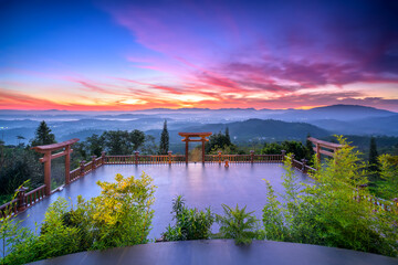 Fototapeta na wymiar Dawn in front of temple gate with impressive colorful clouds in sky shines under mist valley to attract tourists to relax, meditate near Da Lat , Vietnam