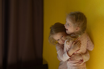  two little sisters hug and laugh