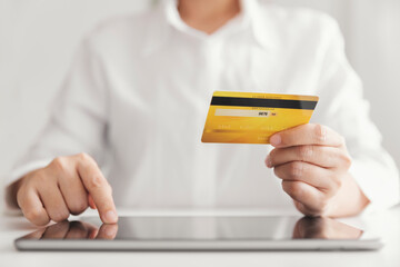 Hands holding credit card and using tablet, Businesswoman working at home, Online shopping, E-commerce, Spending money, Internet banking.