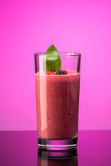 smoothie of berries, banana, milk in a transparent glass on a background of components