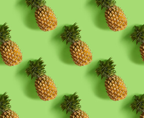 Seamless colorful pattern of pineapples on green color background. From top view. Conceptual modern trendy style. Minimal background