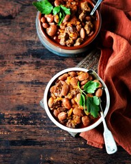Beef stew with beans, tomatoes and vegetables on a dark wooden background