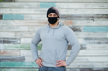 Obraz premium Portrait sports arabian man in black medical face mask and hoodie during coronavirus quarantine.