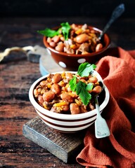 Beef stew with beans, tomatoes and vegetables on a dark wooden background
