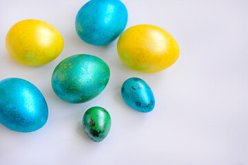 Obraz na płótnie Canvas Close-up of colored eggs of yellow, blue and green color on a white background. Easter. Top view