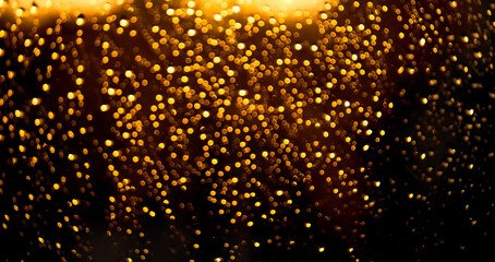 Fototapeta na wymiar Golden sparkling bokeh background on black. Defocused christmas lights, abstract bokeh backdround