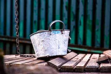 White bucket on weathered wooden planks, rustic well in the countryside