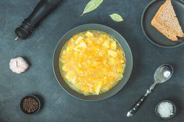 Chicken soup on black bowl on dark black stone table.