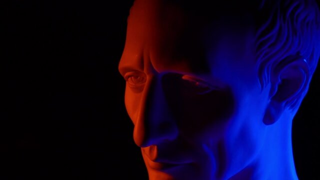 Bust of Julius Caesar in a neon light. Sculpture of Caesar. Blue, raspberry, red, violet light. Neon. Glitch.