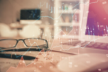 Financial chart hologram with glasses on the table background. Concept of business. Double exposure.