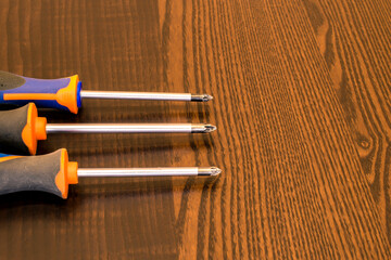 Three screwdrivers are lying on a wooden table