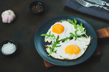 Fried egg. Fried egg with herbs on black plate on black background