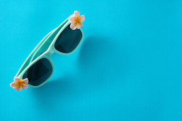 Sunglasses with flowers on blue background. Copy space